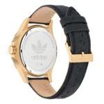 Aukso spalvos „Adidas“ laikrodis su juodu tekstūruotos odos dirželiu, pasižymintis elegantišku dizainu ir logotipu, išgraviruotu ant nerūdijančio plieno nugarėlės.