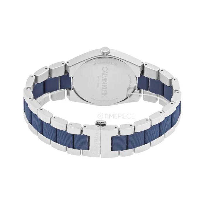 Calvin Klein laikrodžio stambus planas su sidabriniu korpusu ir mėlyna guminė apyranke, pabrėžiantis jo elegantišką dizainą ir prekės ženklą.