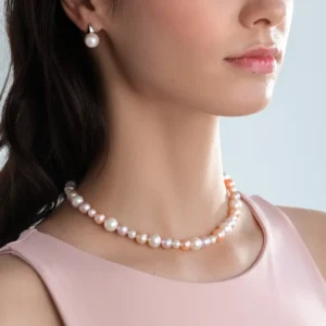 A close-up of a woman wearing a pearl necklace and matching earrings, adorned with soft pink hues, against a light background