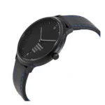 A sleek black Mondaine watch with a minimalist design, featuring a round face, silver hands, and a black leather strap accented with blue stitching.