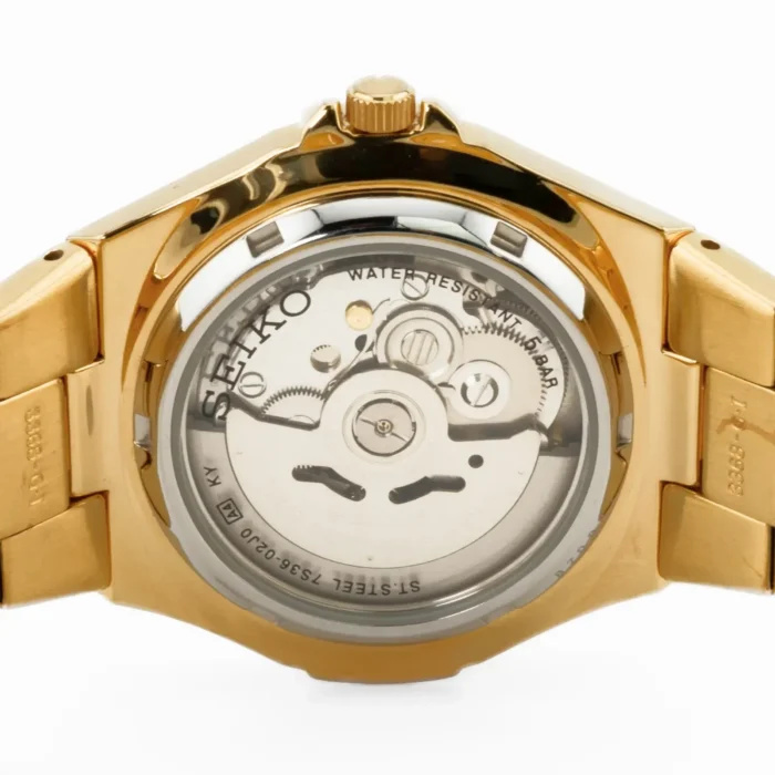 SEIKO SNZE32K1-2 Seiko automaattikellon takanäkymä kultaisessa sävyssä, esittelee sen hienostunutta liikettä ja vedenkestävyysominaisuuksia.