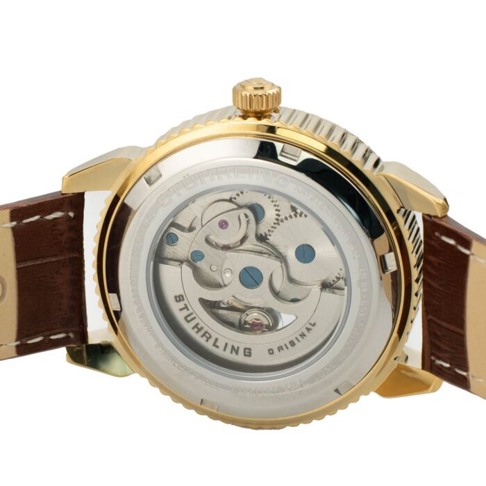En närbild av baksidan på en Stuhrling-klocka, som visar de intrikata kugghjulen och rörelserna genom ett transparent hölje, på ett brunt armband.