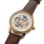 Elegant Stuhrling-klocka med skeletturtavla, detaljer i guldton och brunt läderarmband. Har intrikata kugghjul och romerska siffror.