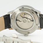 Nerūdijančio plieno automatinio laikrodžio nugarėlė, kurioje matomas sudėtingas mechaninis mechanizmas ir odinis dirželis.