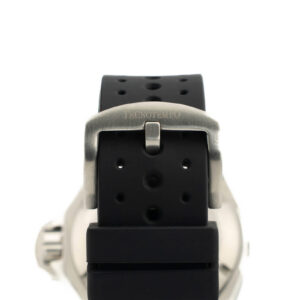 Närbild av ett svart gummiarmband med ett metallspänne ingraverat med “TECNOTEMPO,” som visar perforeringar för justerbarhet.