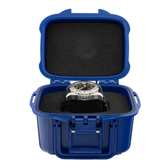 Ruostumattomasta teräksestä valmistettu kello on esillä sinisessä, suojatussa säilytyskotelossa, jossa on pehmustettu sisäosa ja turvallinen lukitus.