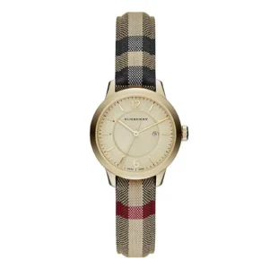 A gold Burberry watch with a minimalist dial and date feature, featuring a plaid fabric strap in beige, black, and red.