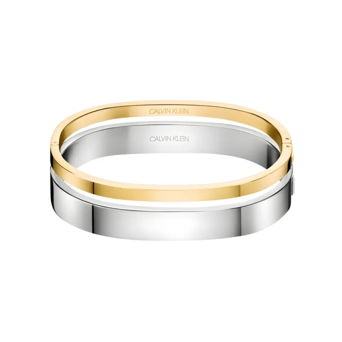 Two sleek bangles, one gold and one silver, featuring the Calvin Klein logo, stacked elegantly on a white background.