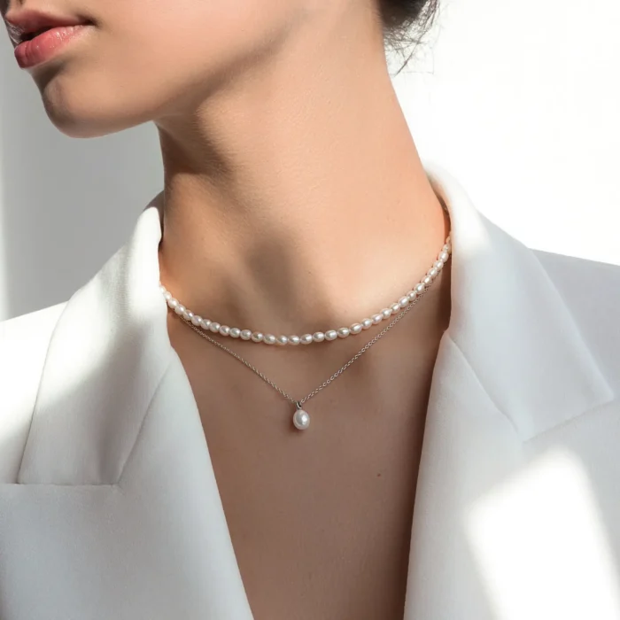 Close-up of a woman wearing a chic white blazer, layered pearl necklaces, highlighting elegance and sophistication.