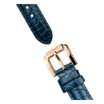 Close-up of a blue crocodile leather watch strap with a gold-tone rectangular buckle and two adjustment holes.