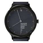 Lähivõte Mondaine Helvetica Swiss Made kellast, millel on stiilne must numbrilaud, minimalistlik disain ja tumesinine nahkrihm.
