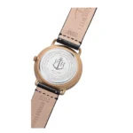 Back view of a bronze watch with a white dial, featuring an anchor logo, black leather strap, and stamped details on the underside.