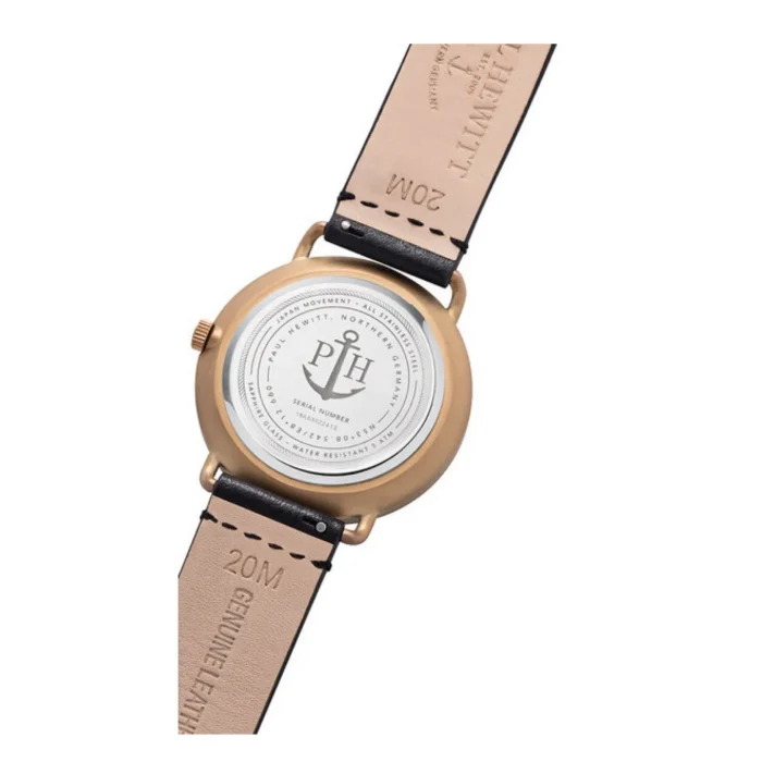 Back view of a bronze watch with a white dial, featuring an anchor logo, black leather strap, and stamped details on the underside.