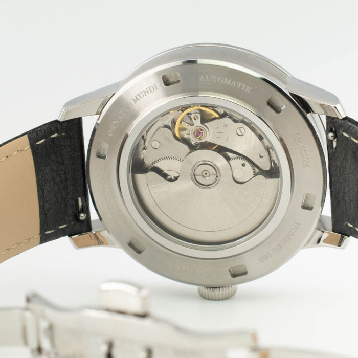 Close-up of a stainless steel automatic watch back, showcasing intricate mechanical movement and a leather strap.