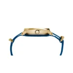 Close-up of a gold wristwatch featuring a blue woven strap and a crown for adjusting time, highlighting its elegant design.