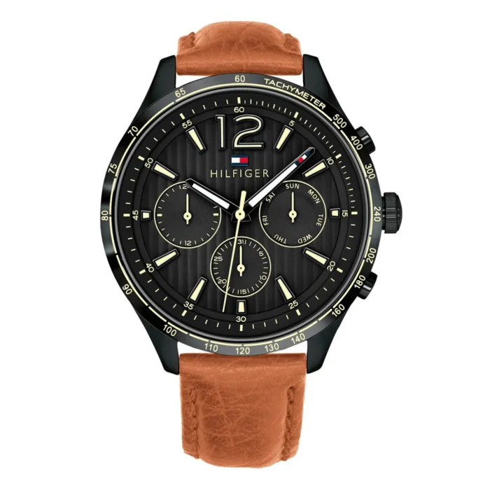 Black and gold Tom Hilfiger watch with a tachymeter, featuring three sub-dials and a brown leather strap. Stylish and modern design.